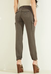 Khai byxor med elastiska muddar, flera fickor och en logotyppatch på baksidan. Tillverkade av mjukt, strukturerat tyg.