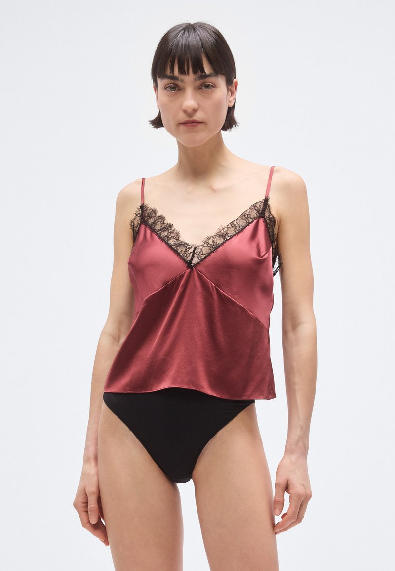 Tumši sarkana satīna kamizole ar melnām mežģīnēm pie V-veida izgriezuma, ar regulējamām plānām lencītēm un vaļīgu, plūstošu dizainu.