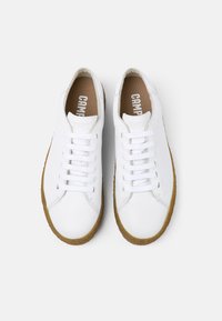 Sneaker bianche in pelle con punta tonda, sei fori per i lacci e chiusura con lacci. Suola in gomma color talpa con una sottile texture. La soletta presenta il logo "CAMPPER".