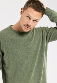 Pull en laine vert clair avec un col rond et des manches longues, présentant un tricot texturé et une coupe décontractée.