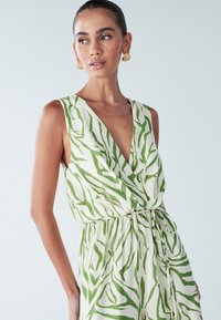 Abito senza maniche verde e bianco con scollo profondo a V, design avvolgente e tessuto strutturato con motivo a strisce di tigre.