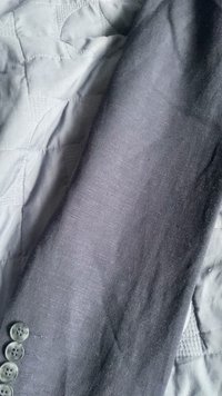 Harmaa pellavakankaan hihna, jossa on sileä pinta; hihassa on kuusi vaaleanharmaata nappia; aseteltu vaaleanharmaan tikatun pinnan päälle.