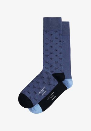 Calcetines en azul marino y azul claro con un patrón de tijeras. Un calcetín es de color azul marino sólido con detalles en negro; el otro tiene un puño azul claro.