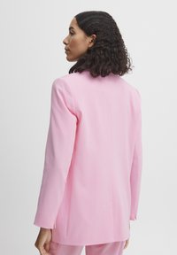 Pink blazer with a tailored design, featuring long sleeves and a smooth texture; back view showing minimalistic stitching detail.