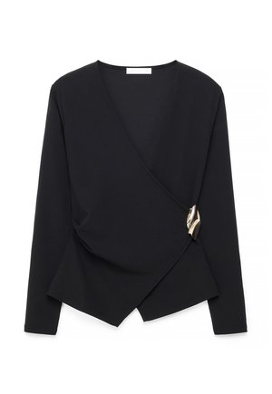 Čierna dlhá blúzka s prekladaným strihom, asymetrickým lemom a dekoratívnou zlatou sponou na pravej strane.