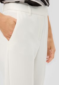Witte broeken met een soepele textuur en een verborgen tailleband, voorzien van zijzakken en een elegante, op maat gemaakte pasvorm.