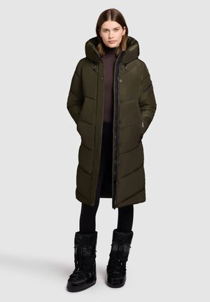 Abrigo largo de plumas verde oliva con capucha y cremallera frontal, con un diseño acolchado y bolsillos laterales, combinado con botas negras aisladas.