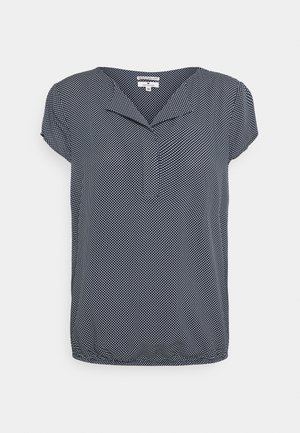 Blouse bleu marine à manches courtes avec des pois blancs et un petit col plié au niveau du décolleté.