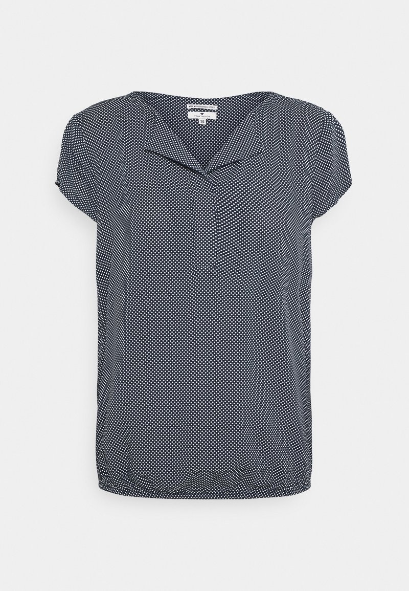 Blouse bleu marine à manches courtes avec des pois blancs et un petit col plié au niveau du décolleté.