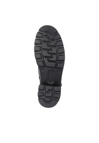Suela de zapato de goma negra con un patrón de textura, que presenta surcos en zigzag para mayor tracción y un logo de marca en relieve cerca del talón.