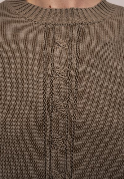 Κοντινό πλάνο πλεκτού πουλόβερ ταουπέ με κεντρικό σχέδιο κοτσίδας και ριμπ ζιβάγκο.