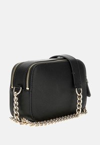 Piccola borsa a tracolla nera con texture, dotata di due scomparti con cerniera e tracolla a catena in tono oro su uno sfondo bianco.