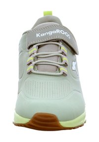 Hellgrauer Sportschuh mit glattem, synthetischem Obermaterial, durchbrochener Gestaltung, flexibler Sohle und gelb-grünen Akzenten. Velcro-Verschluss.