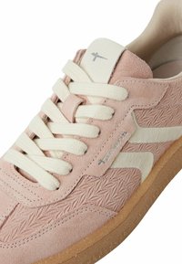 Heled roosa suede spordijalatseid valgete kanvasdetailidega, tekstuurse viimistlusega, kreemjate paeltega ja mustriga keskmise tallaga, mis on pruunikas.
