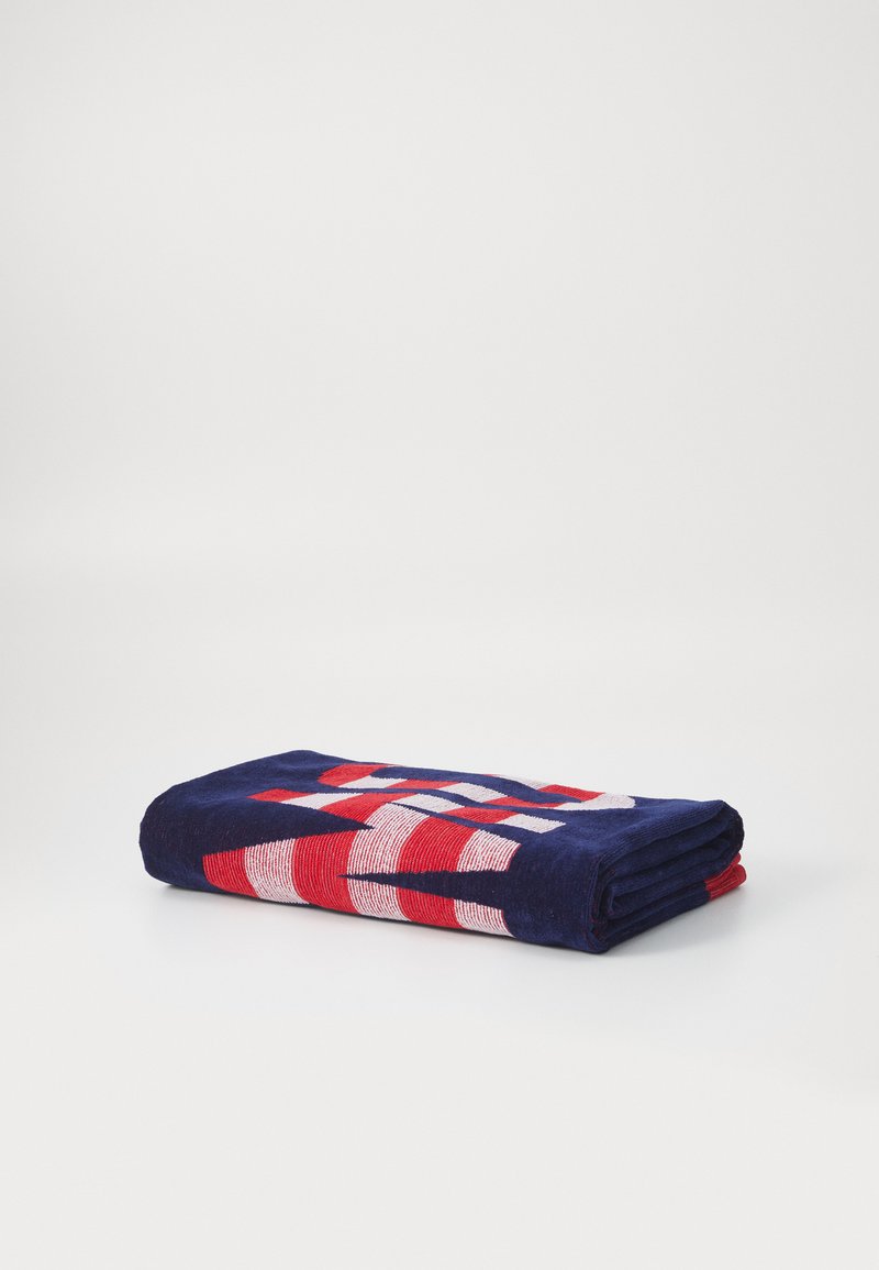 Serviette bleu marine avec un motif à rayures rouges et blanches, pliée soigneusement. Fabriquée en tissu doux, avec une texture épaisse et absorbante.