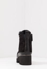 Stivali alla caviglia in suede nero con punta arrotondata, bordo in pelliccia testurizzata nella parte superiore e tacco spesso a coste. Chiusura con zip laterale per una vestibilità facile.