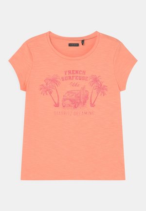 T-shirt corail à manches courtes avec col rond, présentant un motif rose de palmiers, van, planches de surf et texte « French Surfeuse Biarritz Dreaming ».