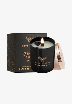 Zwarte keramische kaars met een houten lont, aangestoken, met een gouden deksel. Doos toont een zwart en goud ontwerp met tekst: "CRYSTALLOVE, zwarte obsidian & oud."