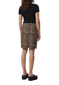 Zwart kortemouwtop gecombineerd met een knielange leoprintenrok in bruin en beige tinten, aangevuld met zwarte platformsandalen.