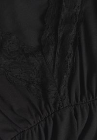 Blusa preta com renda ao longo do decote, tecido suave, seção franzida na cintura, textura lisa e design opaco.