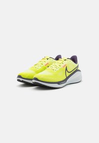 Neoonkollased Nike jooksujalatsid mustade taldade ja lilla sisetallaga valgel taustal.