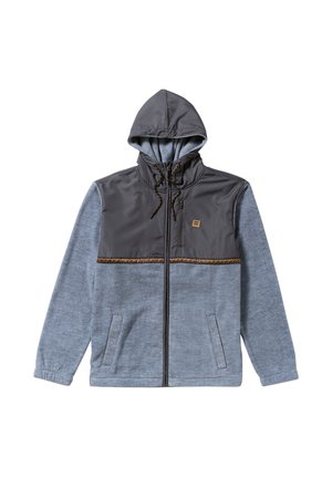 Jachetă cu glugă, cu partea superioară din nylon gri și partea inferioară din fleece albastru. Dispune de un fermoar, două buzunare laterale și o bandă decorativă maro.