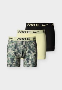 Τρία ζευγάρια ανδρικά εσώρουχα μπότερ της Nike σε καμουφλάζ, ανοιχτό κίτρινο και μαύρο, με λάστιχα μέσης με λογότυπο, τοποθετημένα το ένα πάνω στο άλλο σε απλό φόντο.