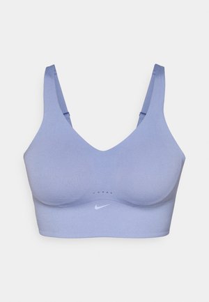 Soutien-gorge de sport violet clair avec une texture lisse, décolleté en V profond, larges bretelles et logo Nike en blanc. Détails en panneau en mesh à l'avant.