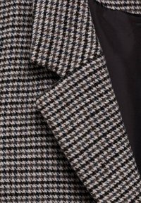 Houndstooth patterned fabric in shades of brown and black with a soft texture. Includes a dark lining, showing tailored details and stitching.