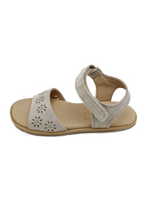 Sandalia de ante beige con diseño floral calado en la correa delantera, correa ajustable en el tobillo con velcro y suela plana.
