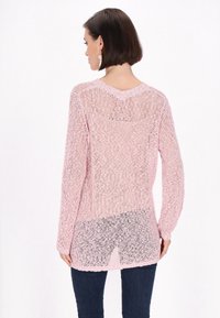 Roze gebreide trui met een losse, open structuur, lange mouwen en een V-vormige achterkant; heeft een gesplitste zoom aan de achterkant.