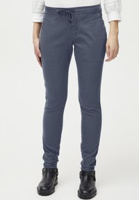 Pantalones jogger de algodón elástico en azul con cintura ajustable y diseño slim-fit, complementados con botas de tobillo negras.