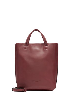 Sac rectangulaire en cuir bordeaux avec deux courtes poignées, couture minimale et une bandoulière amovible. Nom de la marque embossé à l'avant.