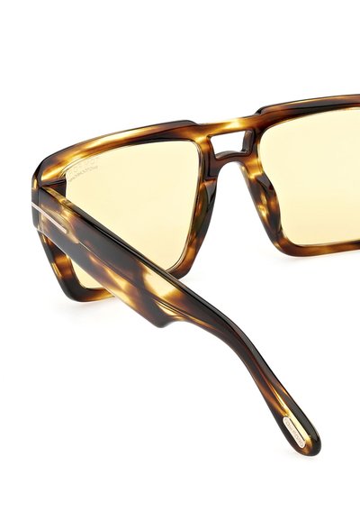 Želvovinové sluneční brýle s tlustým, hranatým rámem a žlutě tónovanými skly. Vyznačují se jedinečným designem a hladkým povrchem.