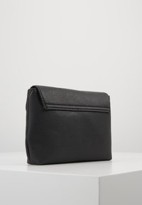 Svart läderkuvertväska med pebble-textur, rektangulär form och lockstängning. Har en dragkedjeficka på baksidan.