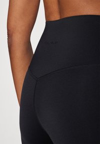 Sorte høytlivs leggings med en glatt tekstur, med en subtil logo "ONLY PLAY" nær livlinjen og dekorative sømdetaljer.