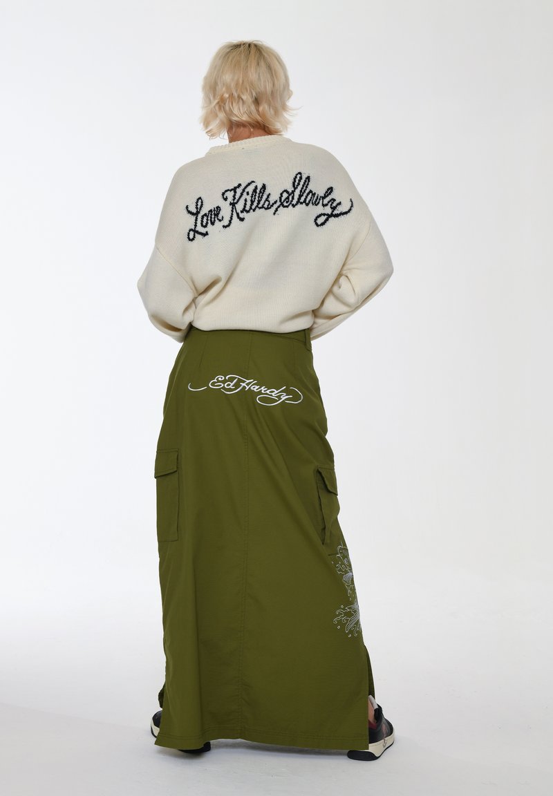 Cremefarvet strikket sweater med "Love Kills Slowly" på ryggen, parret med en lang olivengrøn cargo-nederdel med lommer og "Ed Hardy" detalje.