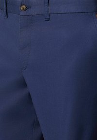 Námořnické modré kalhoty vyrobené z hladkého materiálu, s knoflíkovým zapínáním, rovnou přední částí a postranními kapsami. Viditelné jednoduché švy.