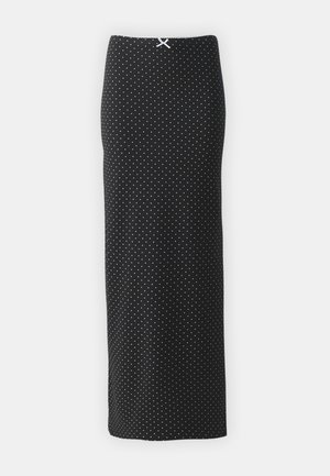 Falda negra con lunares hecha de una tela suave, con un diseño recto, longitud hasta el tobillo y un pequeño lazo blanco en la cintura.