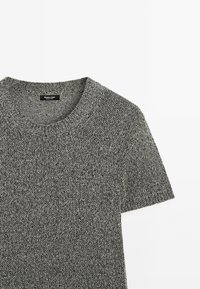 Szary, dziergany sweter z krótkim rękawem i okrągłym dekoltem. Tkanina ma fakturowane wykończenie oraz subtelne połączenie ciemnoszarych i jasnoszarych nici.