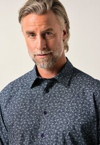 Pánská košile na knoflíky v tmavě modré barvě s texturovaným vzorem a fialovými knoflíky. Má špičatý límeček a dlouhé rukávy.