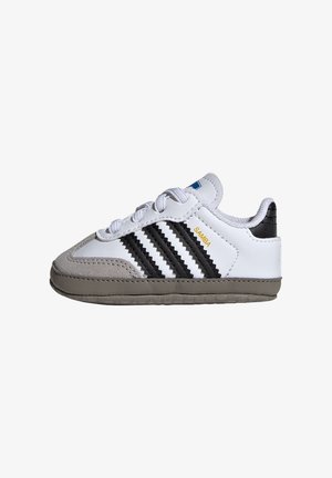 Hvid og grå toddler-sneaker med sorte striber, snørebånd og guld "SAMBA" tekst på siden.