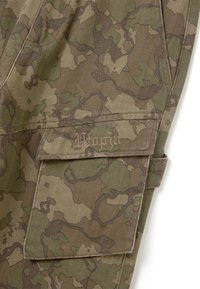 Camouflage-Musterstoff in erdigen Tönen von Braun und Grün, mit einer Klappentasche, die den Text "Utopia" in einer dekorativen Schriftart zeigt.