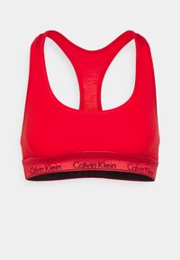 Rød sports-BH laget av glatt stoff, med racerback-design og en svart stropp med "Calvin Klein"-logo. Ingen synlig polstring.