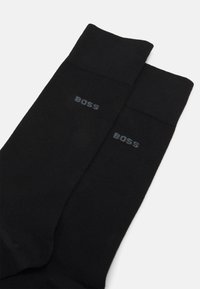 Sorte crew socks med ribbet tekstur. Har grå "BOSS" logo trykt på hver sok. Enkel design, blødt materiale og ensartet farve hele vejen igennem.