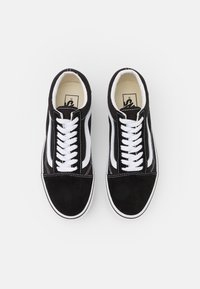 Black suede sneakers with white lace-up closure, white side stripe, and cream-colored insole. Classic low-top design with contrasting details.
