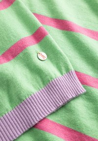 Groen en roze gestreepte gebreide stof met een lila geribde manchet en een klein rond wit label met een roze hertenlogo.