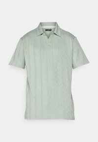 Polo verde-claro com mangas curtas, apresentando um padrão de diamante texturizado e colarinho. Feito de um material macio. Marca: Brave Soul.