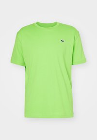 T-shirt in cotone verde brillante con scollatura rotonda, maniche corte e un piccolo logo ricamato sul petto. Design semplice e classico.
