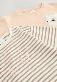 Due felpe: una pesco con una toppa a forma di orso, l'altra crema e marrone a righe con la scritta "IL MIO ORSO FORTUNATO" in lettere rosa. Tessuto morbido.